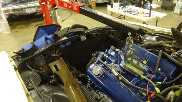 Car engine being lifted with hoist.