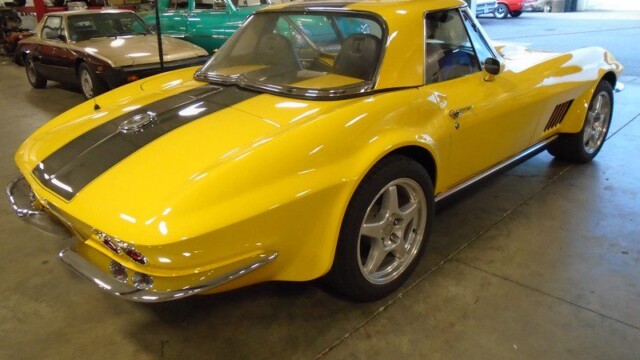 Yellow Corvette convertible in garage.