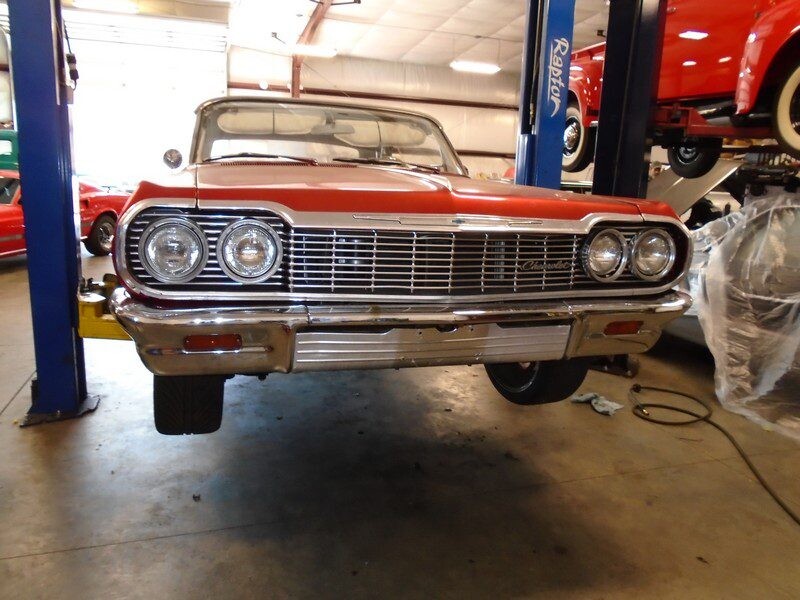 Red classic Chevy Impala convertible on lift.