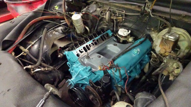 Teal engine in car under repair.