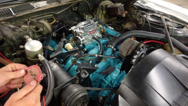 Mechanic working on classic car engine.
