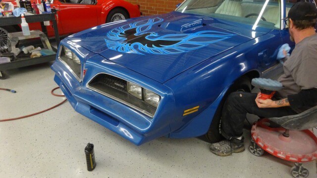 Blue Pontiac Firebird being buffed.