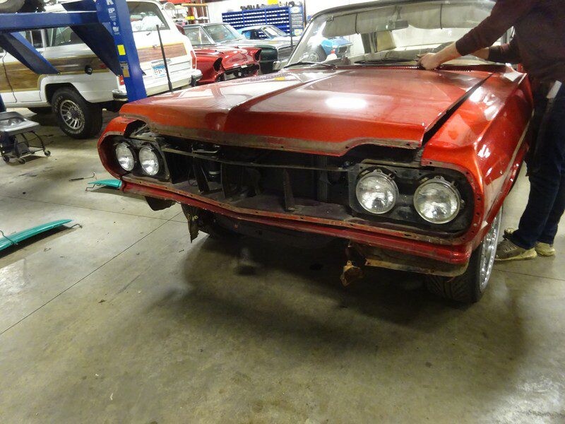 Red classic car undergoing restoration.