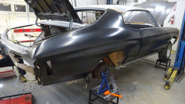 Black classic car body in repair shop.