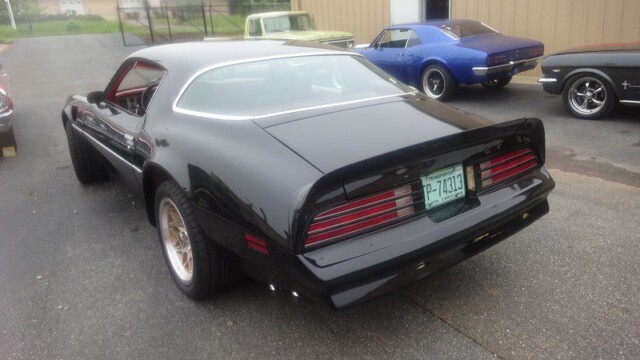 Black Pontiac Trans Am in parking lot.