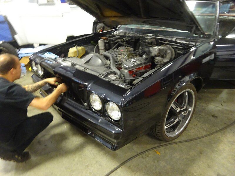 Mechanic repairing a classic car's front.