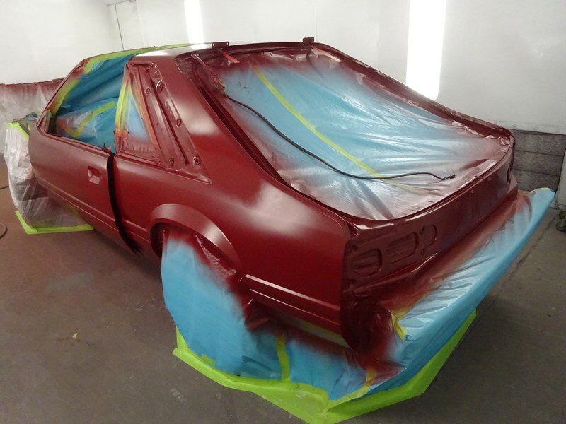 Red Ford Mustang in paint booth.
