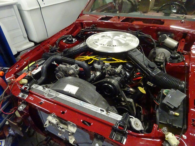 Red car engine bay under repair.