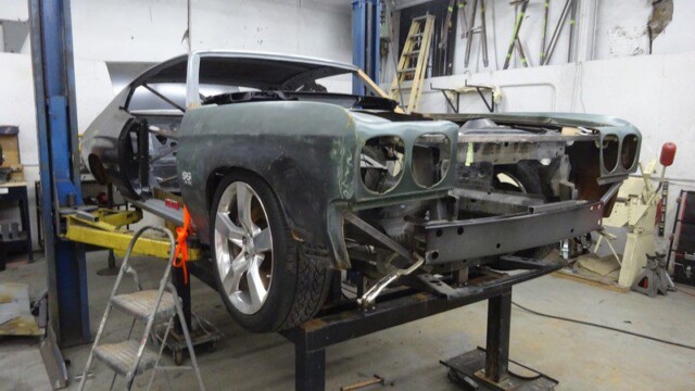 Classic car undergoing restoration in shop.
