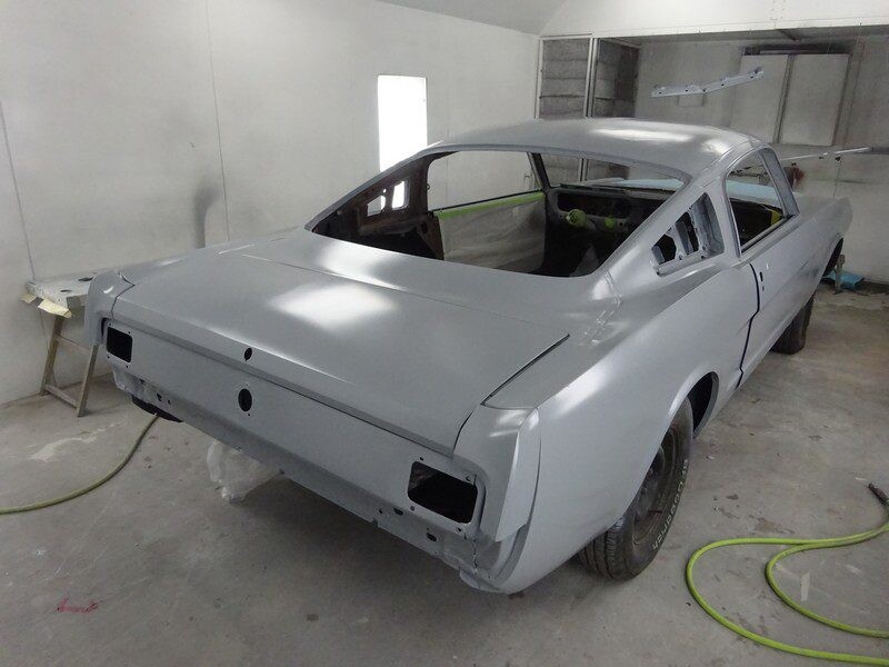 Primered vintage Mustang in a paint shop.
