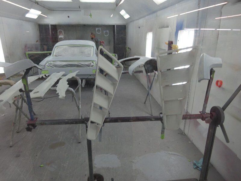 Primed car panels suspended in paint booth