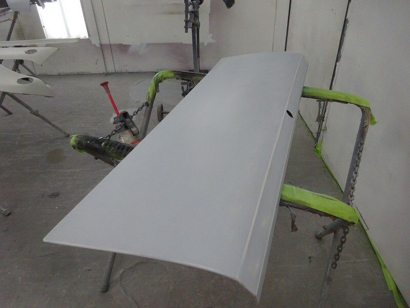 Primed car trunk lid on stand.