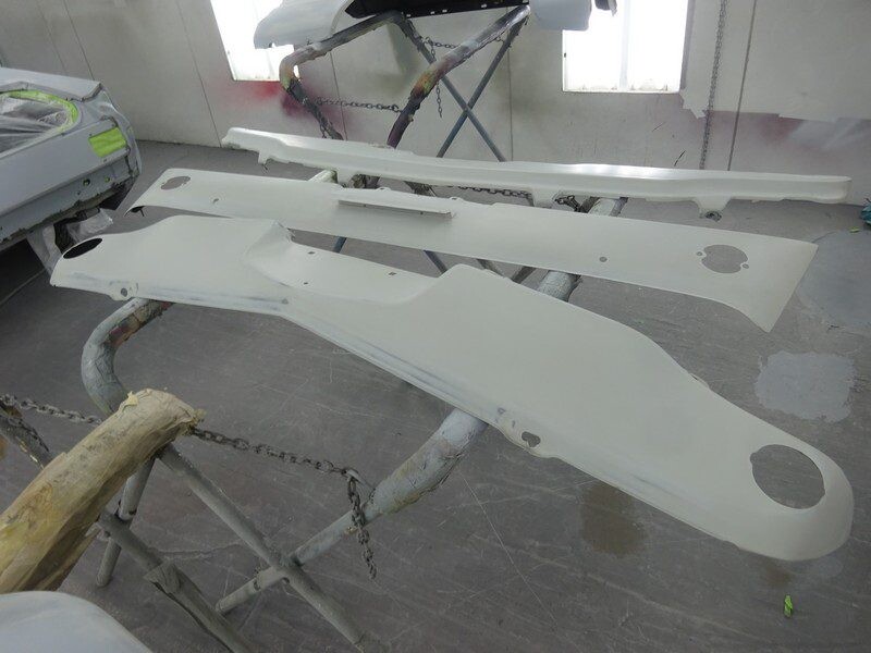 Here's an alt tag for the image: Painted car parts drying on racks.
