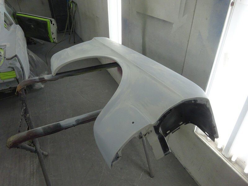 Primed car fender on workbench.