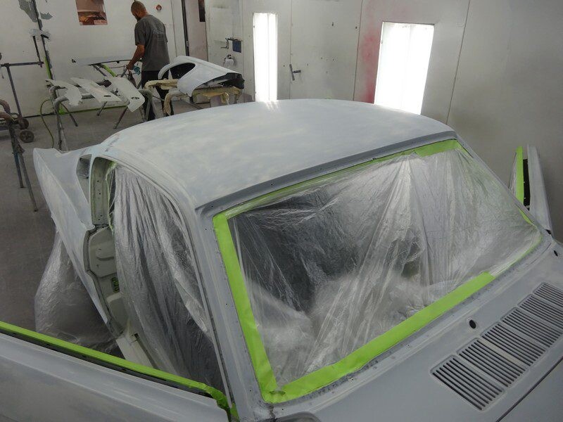 Primered car body in paint booth.