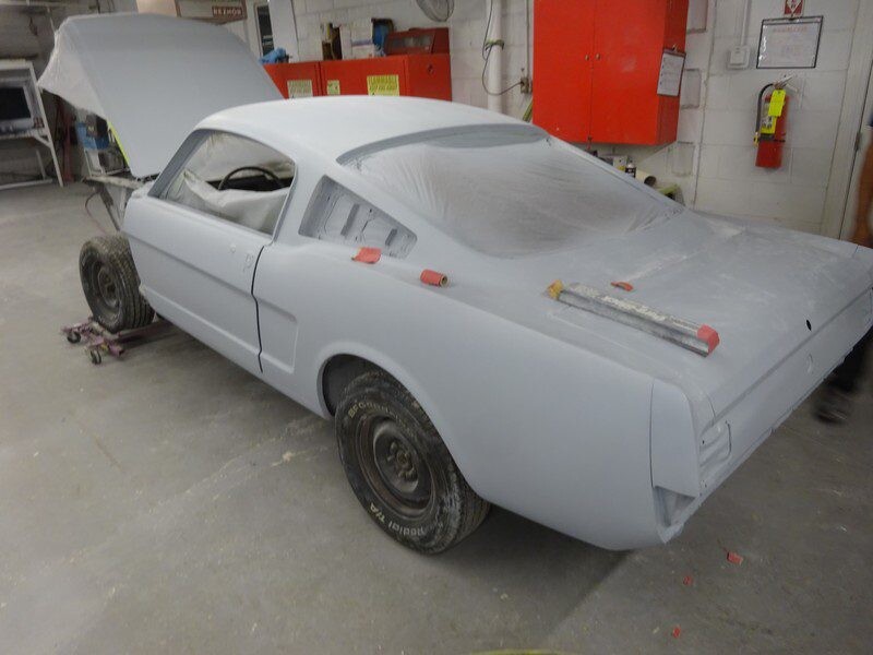Primered Ford Mustang in auto shop.