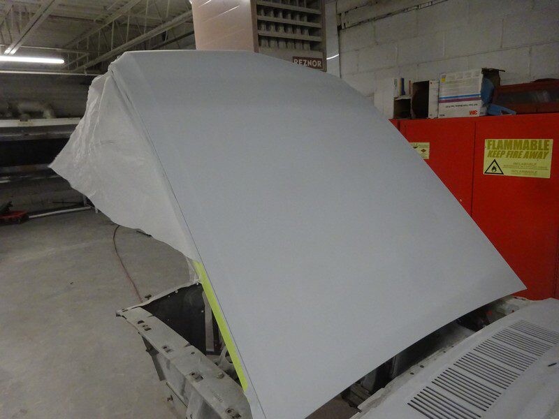 Primed car hood in auto body shop.
