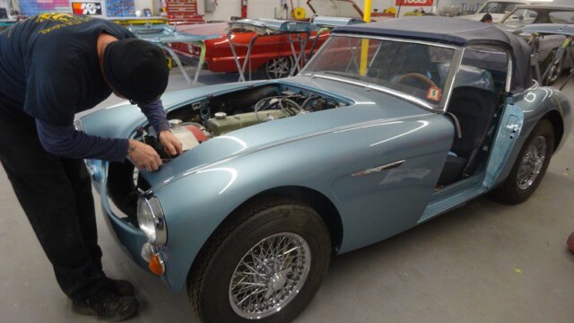 Mechanic working on a blue classic car.