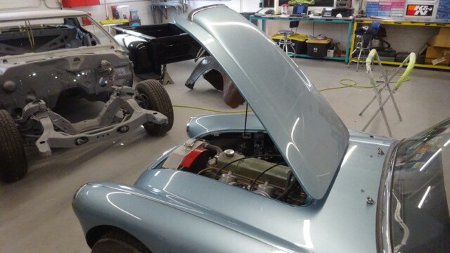 Light blue classic car, hood up.