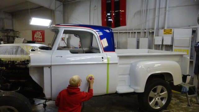 Person sanding a vintage white truck.