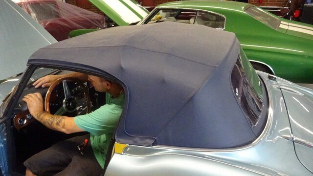 Mechanic installing convertible top in car.