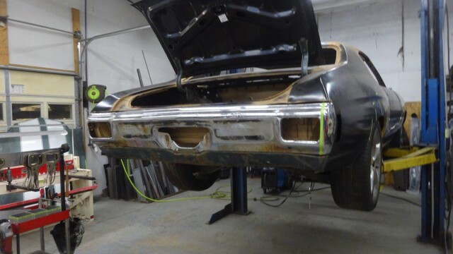 Classic car undergoing restoration in garage.