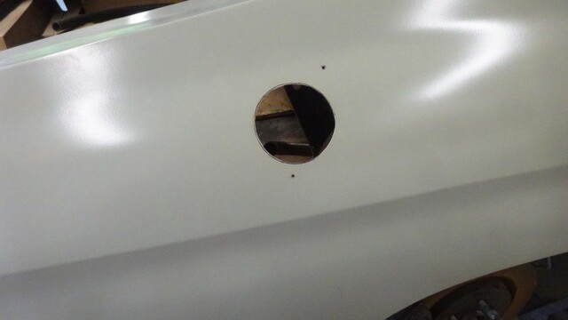 Here's an alt text option for the image: White car body with cut-out hole.