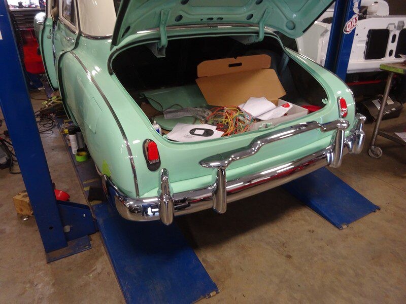 Mint green classic car trunk open.