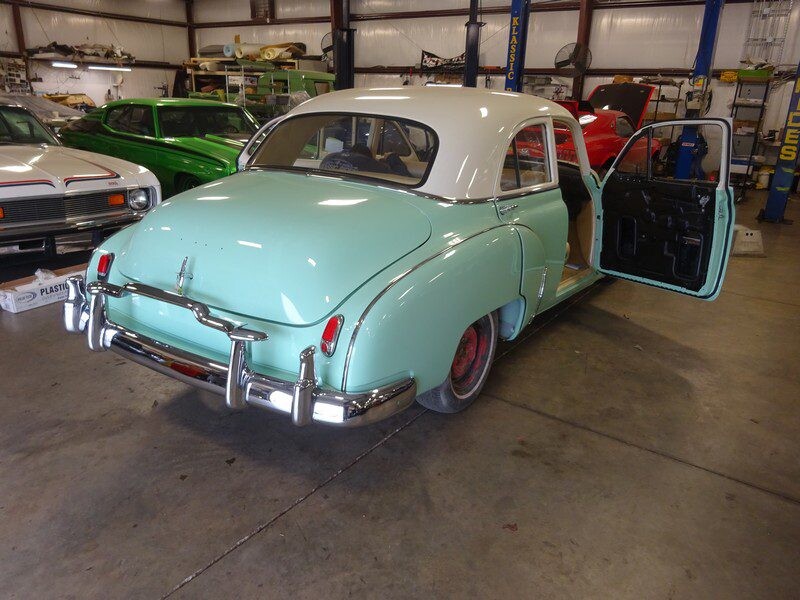 Mint green classic car, door open.