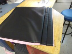 Black fabric on pink foam, being sewn.