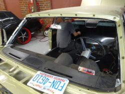 Technician working inside dashboard through windshield