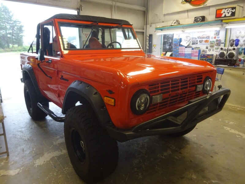 Restored orange Ford Bronco in shop.