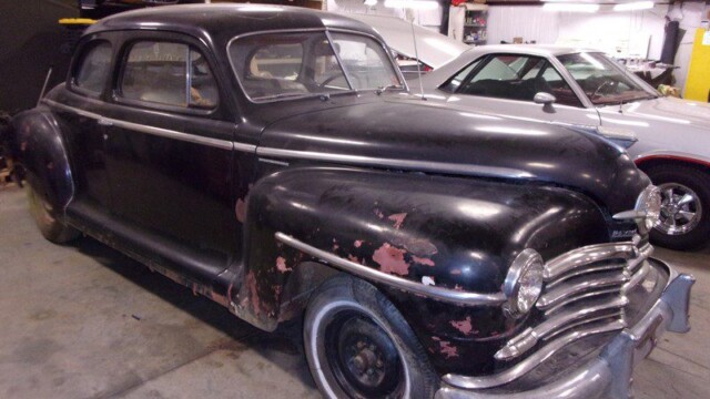 Black vintage Plymouth coupe, needs restoration.