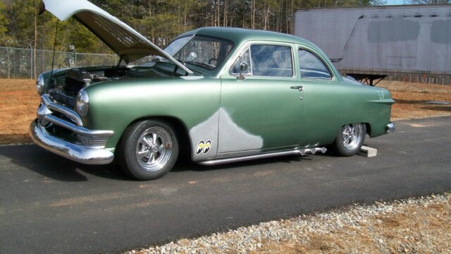 Custom green Ford, hood up.