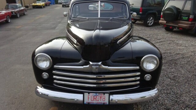 Black 1940s Ford coupe, front view.