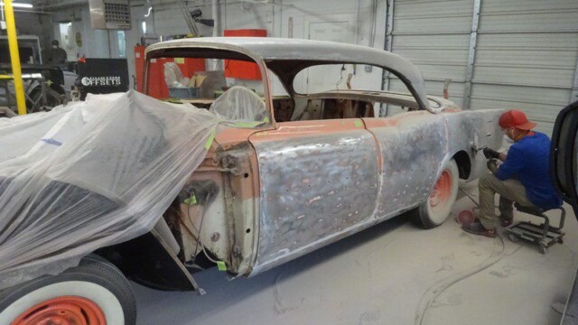 Worker sanding body panels on classic car