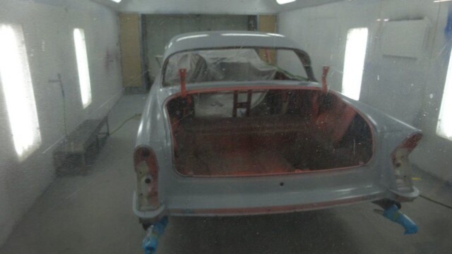 Primer-coated vintage coupe in paint booth