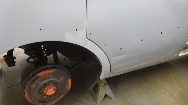 Primered car body on jack stands.