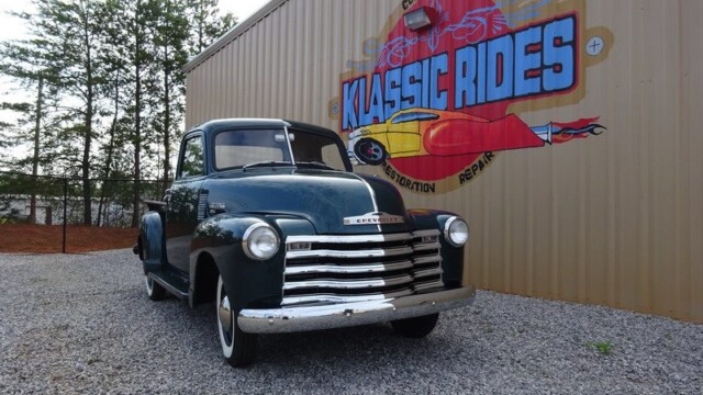 Green classic Chevrolet truck at shop.