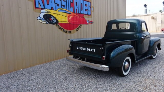 Green Chevrolet pickup truck rear view.