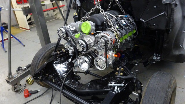 Classic car engine installation in progress.