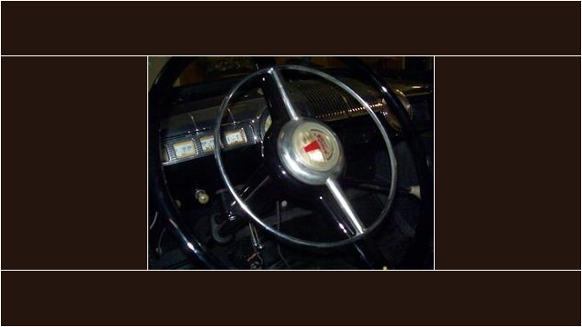 Here's an 8-word alt tag for the image: Classic car's restored black steering wheel and dash.