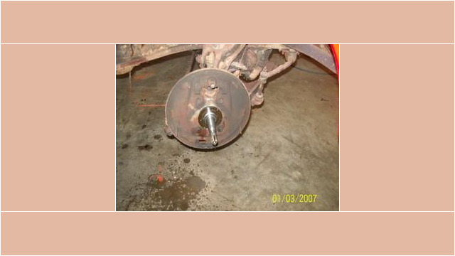 Here's an alt tag for the image: `Rusty car brake drum and axle`