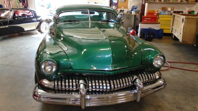 Green classic car in a garage.