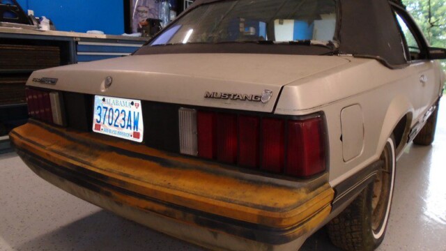 Rusty silver Ford Mustang rear view.