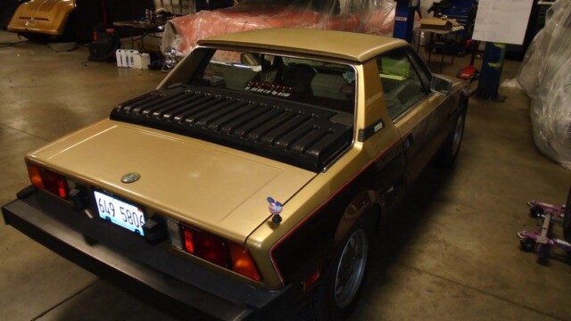 Gold Fiat X1/9 sports car rear view.