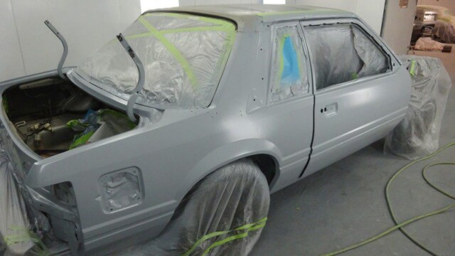 Primered Ford Mustang in paint booth.