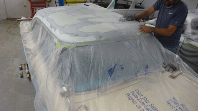 Man sanding car roof, auto body repair.