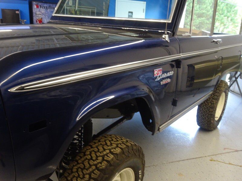 Classic blue Ford Bronco, side view.