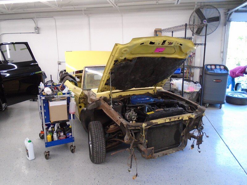 Yellow classic car under repair in garage.